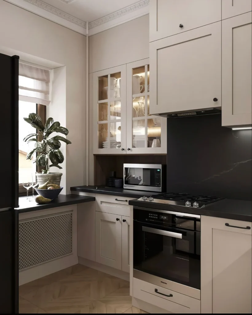 Projekt małej kuchni w bloku z oknem – jasne meble z witrynami, czarny blat i zabudowa grzejnika w eleganckim stylu od Studio Kuziomko.