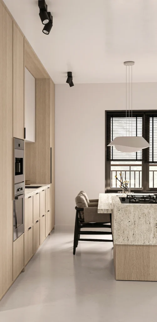 Projekt kuchni z wyspą w bloku – wysoka zabudowa w jasnym drewnie, kamienny blat zintegrowany z płytą grzewczą i nowoczesne oświetlenie od Studio Kuziomko.